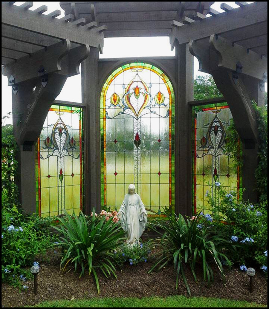 Three arched leaded glass windows set in a garden pergola around a statue of Mary, by Monica Huber